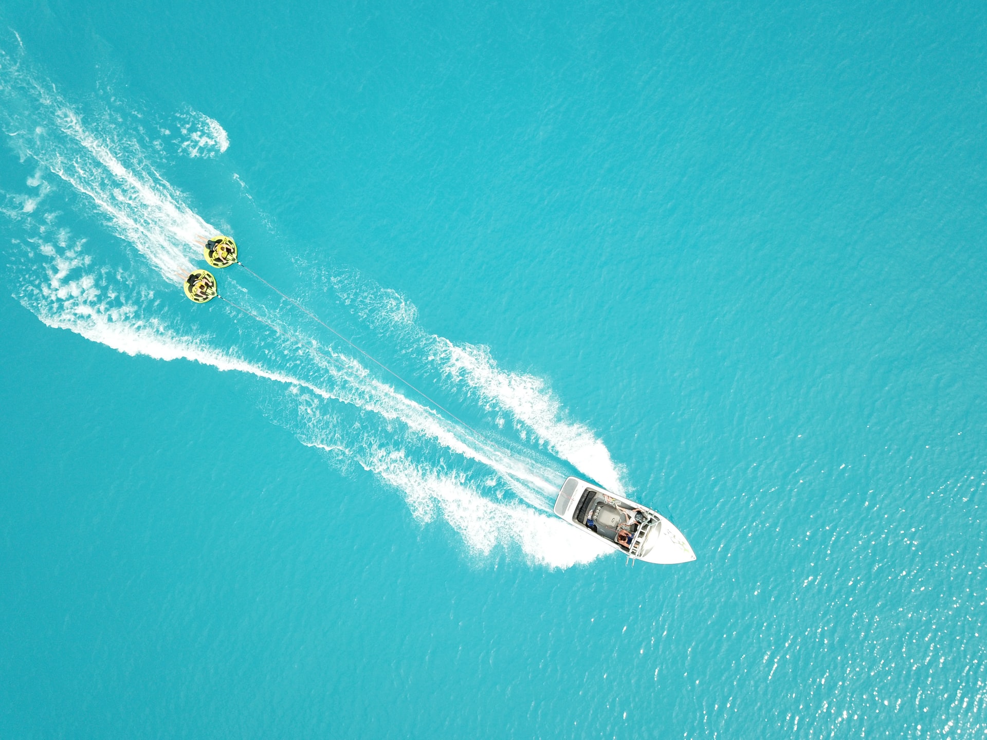 a boat pulling to inner tubes on crystal blue waters.